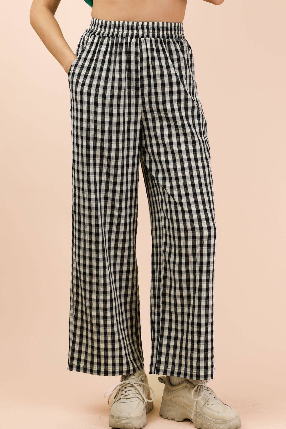 Person wearing black and white checkered pants on a beige background