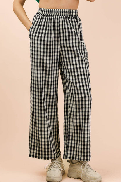 Person wearing black and white checkered pants on a beige background